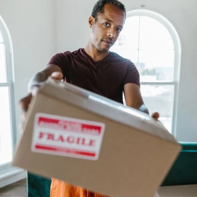 Person carrying a moving box marked fragile